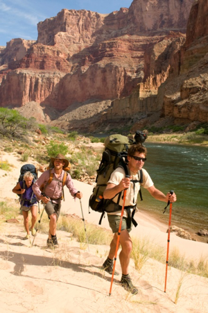 Three hilkers walking along a river in a canyon